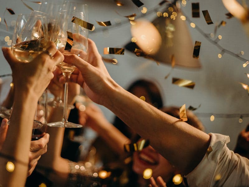 Guests clinking champagne glasses under gold confetti